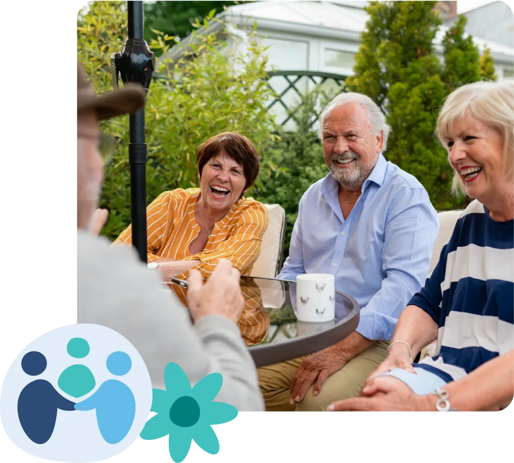 Four elderly people sitting at an outdoor table, laughing and enjoying a conversation