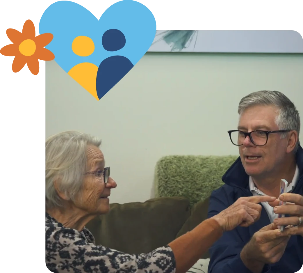 Older woman and man smiling and chatting on a couch in a home setting, representing supportive, client-led care